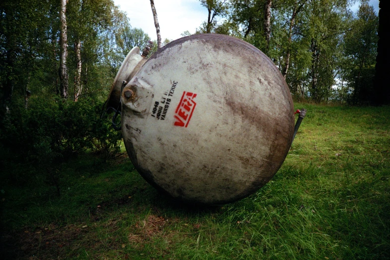 an old, large propane tank in the middle of a field