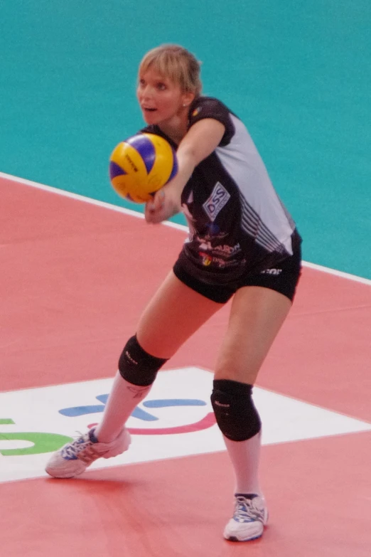 the woman in a volleyball uniform is playing with a ball