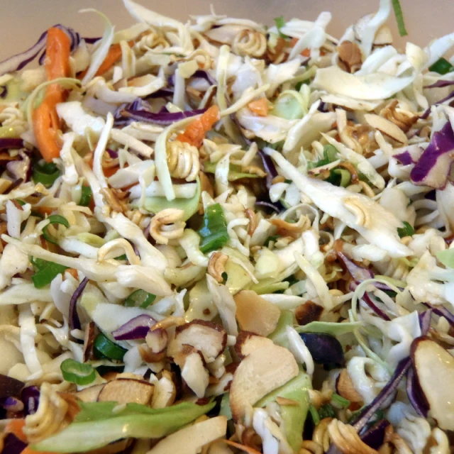 a pile of salad mixed with carrots, onions, and nuts