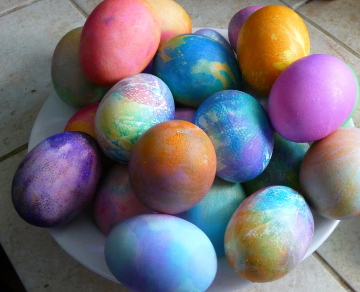 a white bowl full of easter eggs covered in paint
