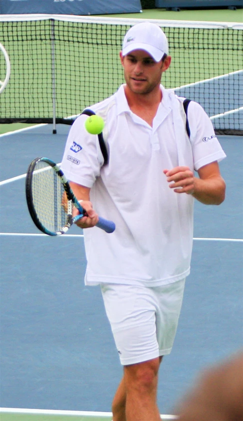 a man in white tennis outfit holding up a tennis racket and ball