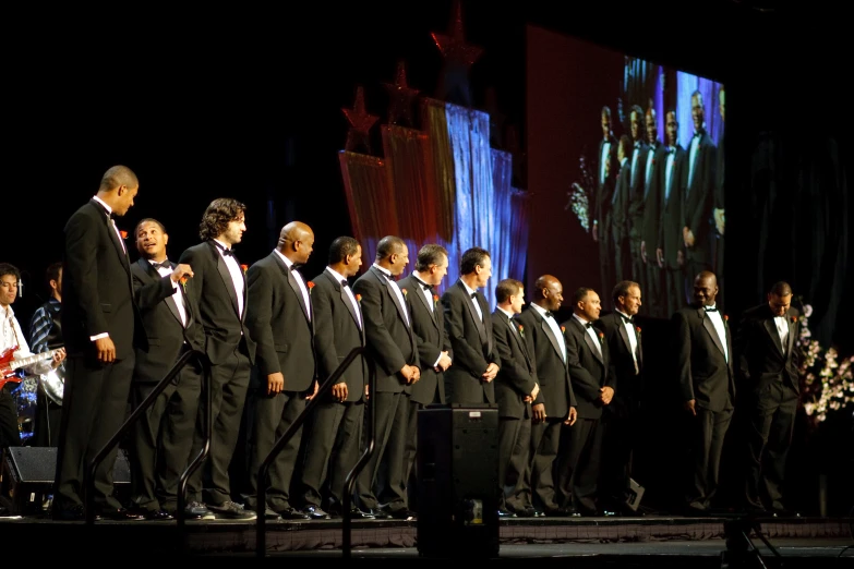 a group of men wearing suits and ties standing on a stage