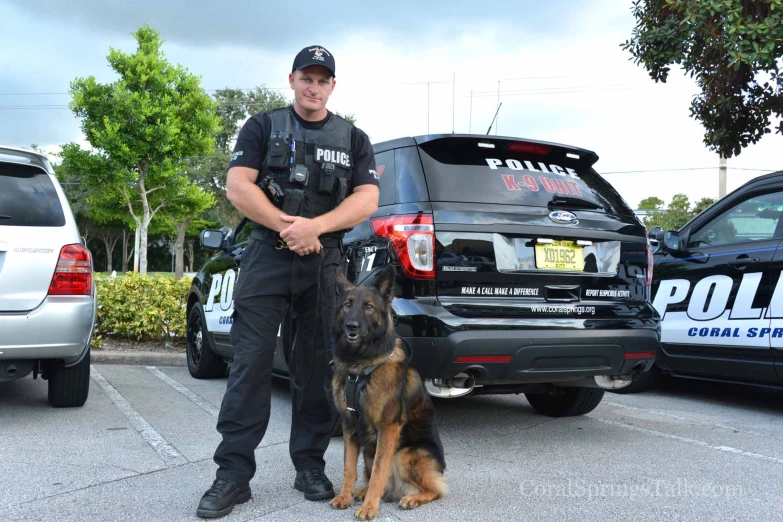 a police officer is posing with his dog in a parking lot