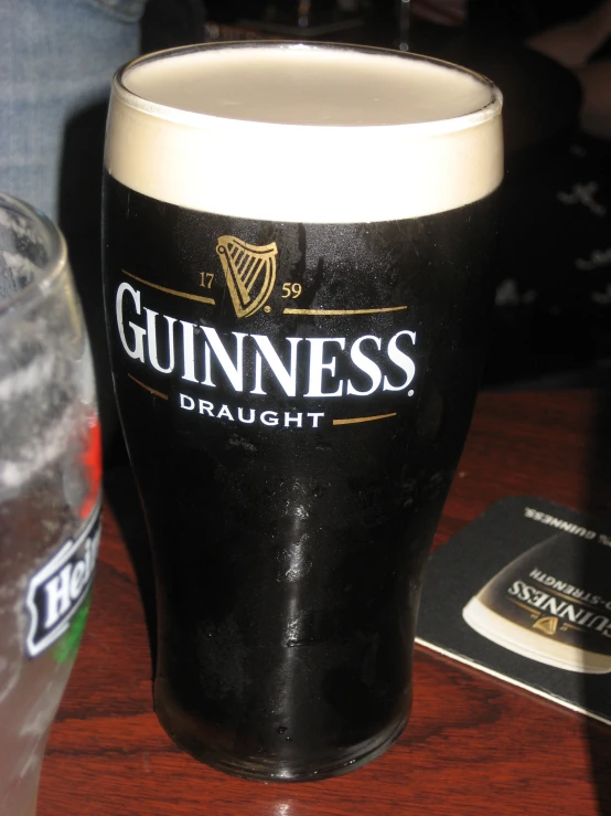 a glass of guinness sitting on a table next to an id card