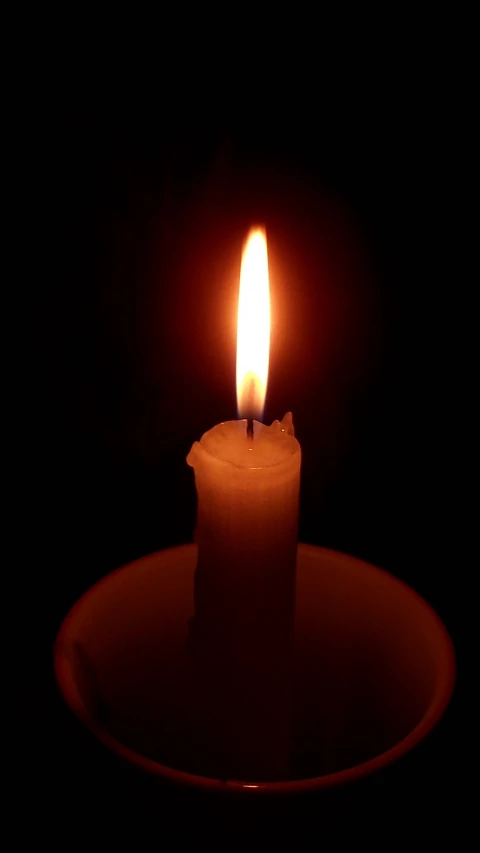 a single lit candle on a small round plate