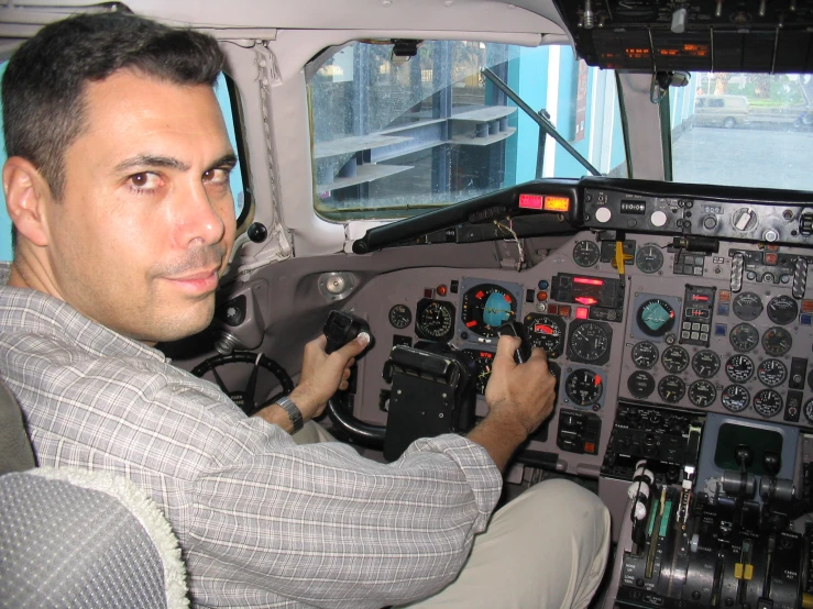 the man is in a plane cockpit holding his hand on the controls