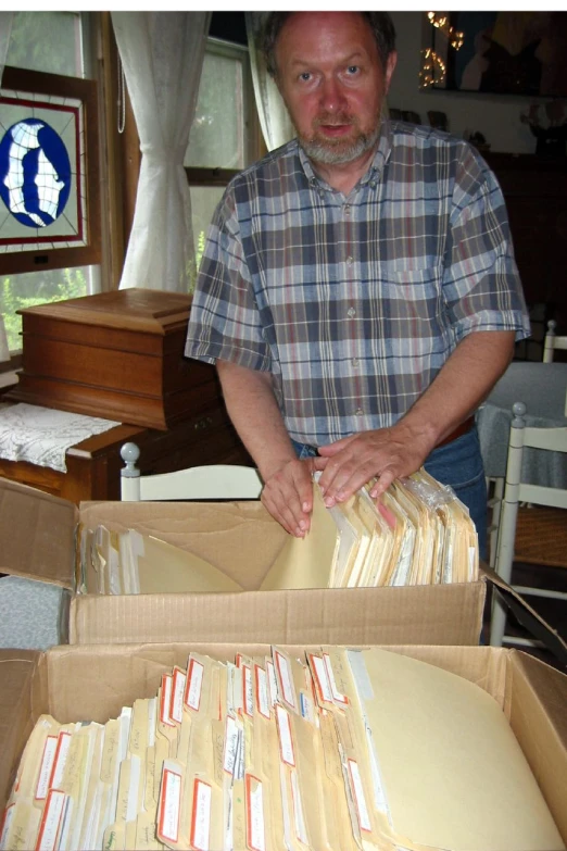 man opening large open box with mail and papers