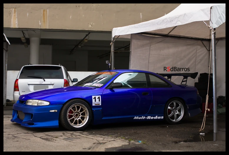 a blue car parked underneath a white tent