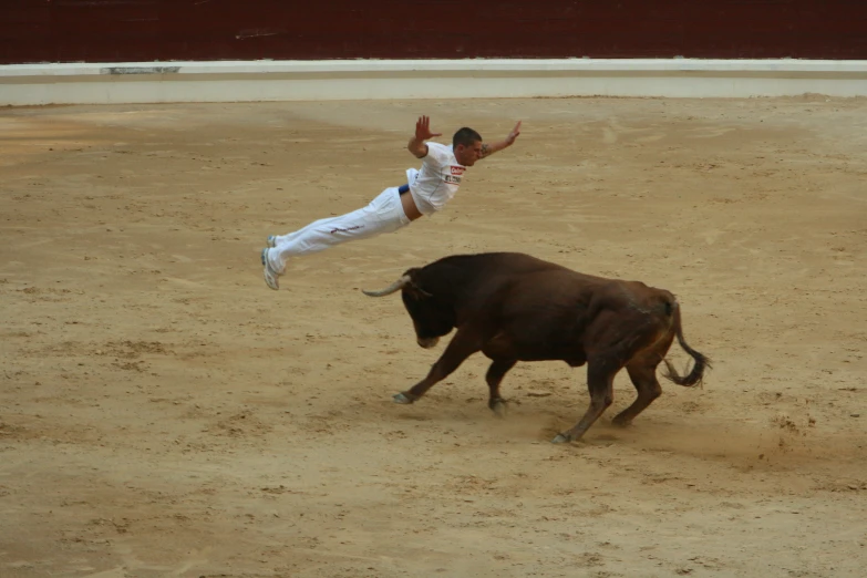 a bull and a man are running in an empty ring