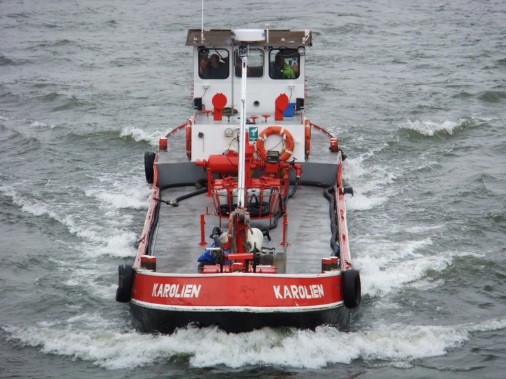 a red boat with a white and black stripe going across the water