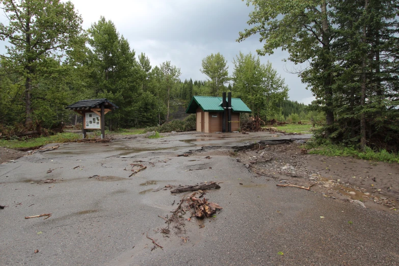 an empty dirt parking lot with signs and trees in the background