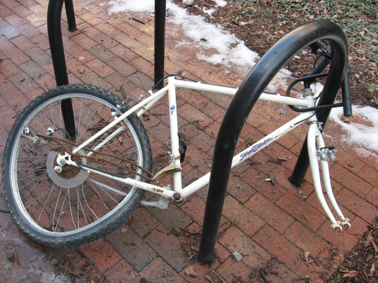 white bicycle on street with snow near pole and fence