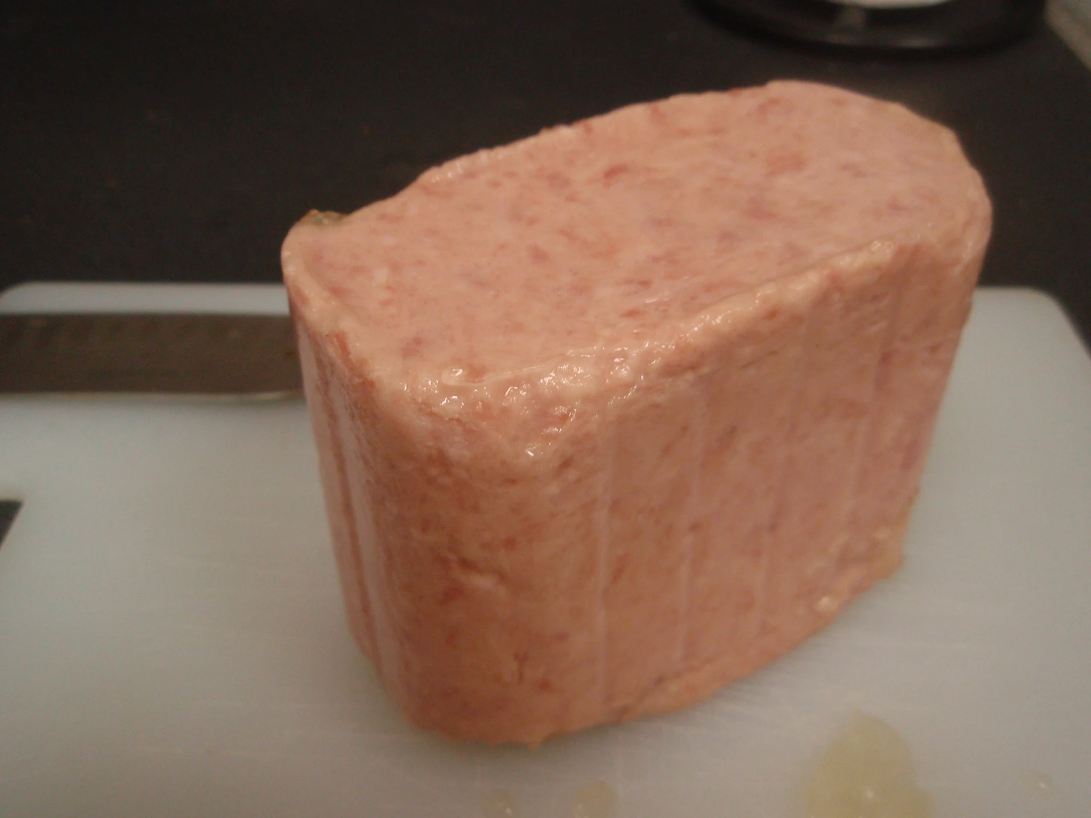 a small square piece of meat sitting on top of a white plate