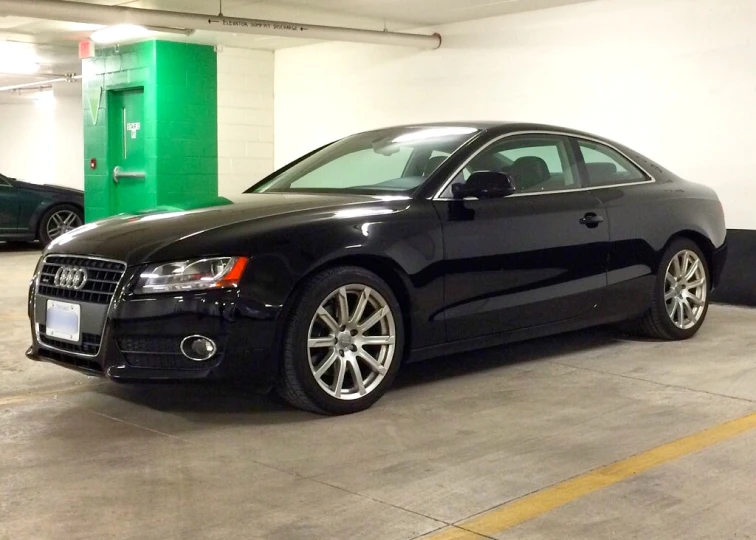 a black car parked in a parking lot with two other cars