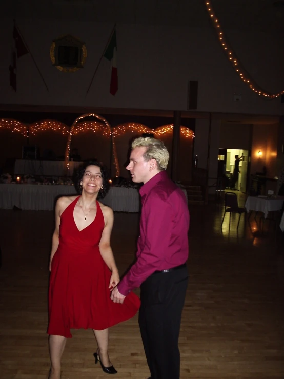 two people wearing red standing in a room with one another