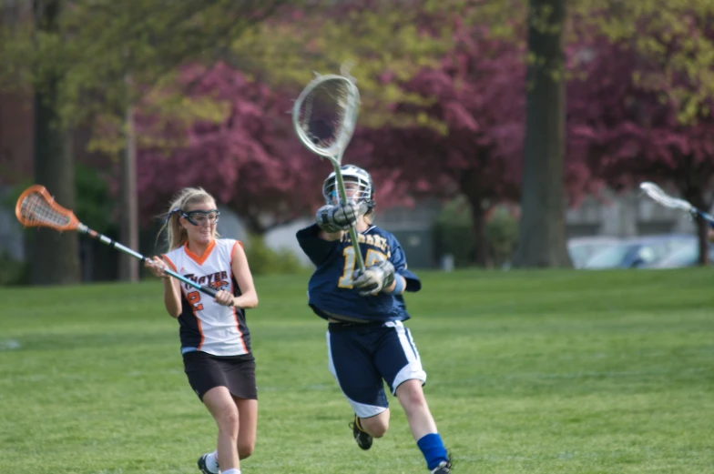 two women in blue uniforms are playing lacrosse