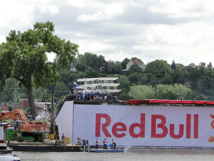 a large red bull sign with people standing around it