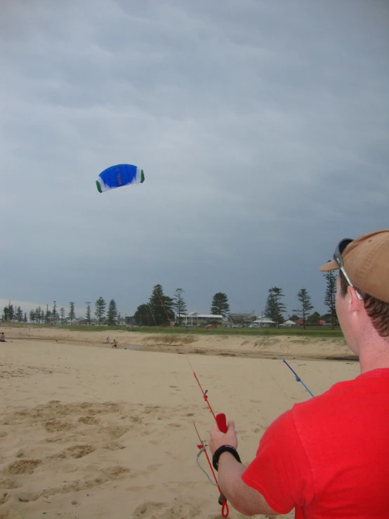 a man holding onto soing while flying a kite on the beach