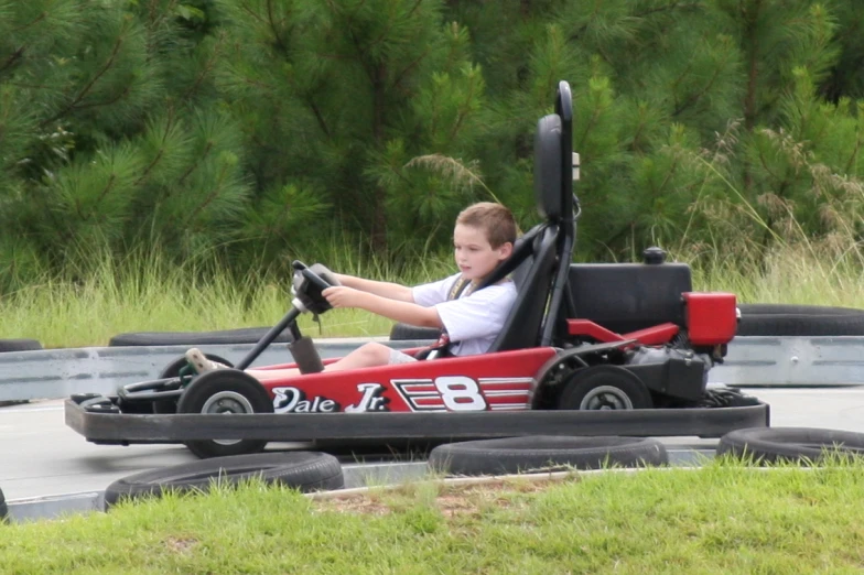 the boy sits in a go - kart on top of the course