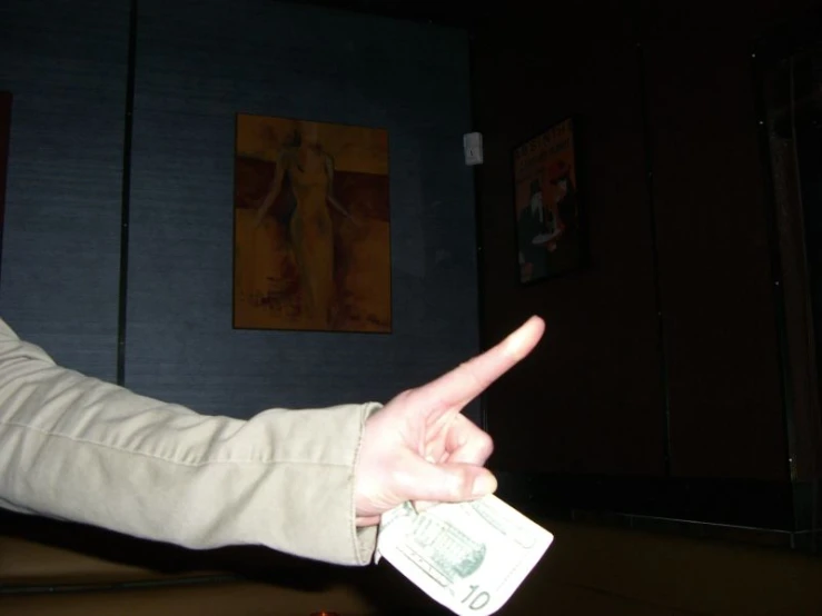 a person with their hand in a rock paper with an index and cross sign pointing toward a dollar bill