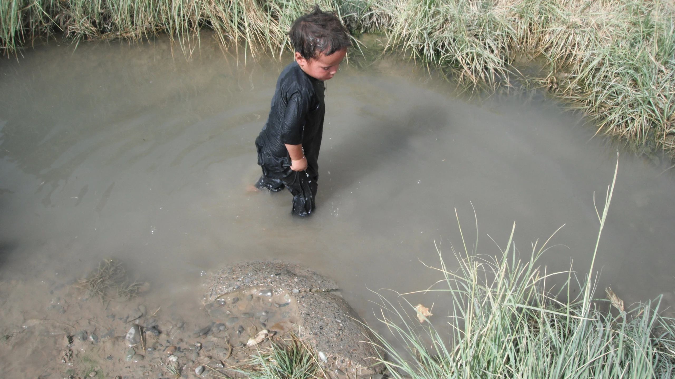 a  with his boots on is wading in the water