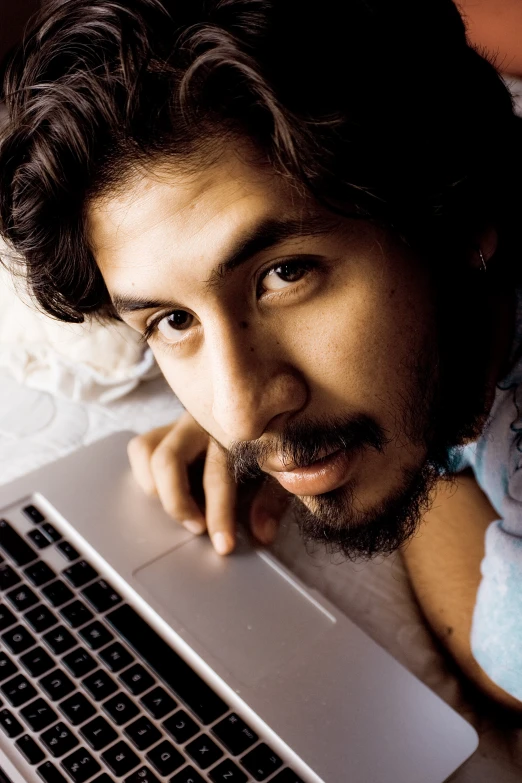 man with curly hair posing for the camera with his laptop