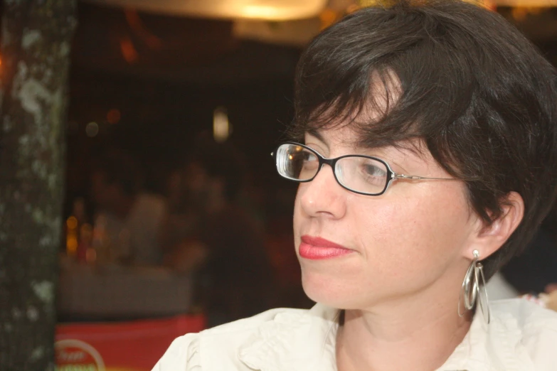 a woman with short dark hair wearing glasses and a white blouse