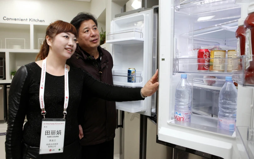 two people standing in front of an open fridge