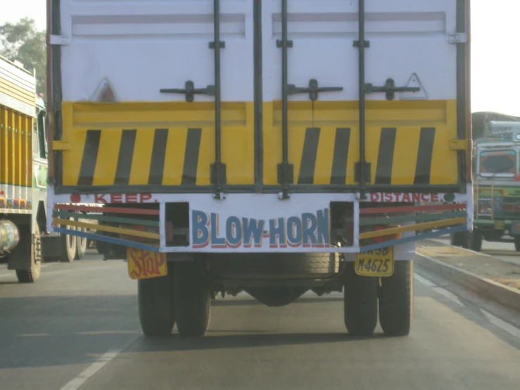 a white and yellow truck traveling down the road