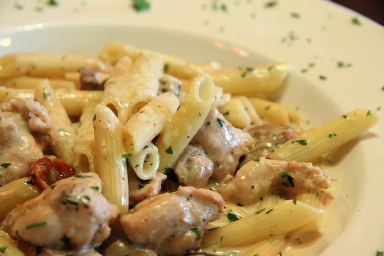 a white plate topped with pasta and meat covered in sauce