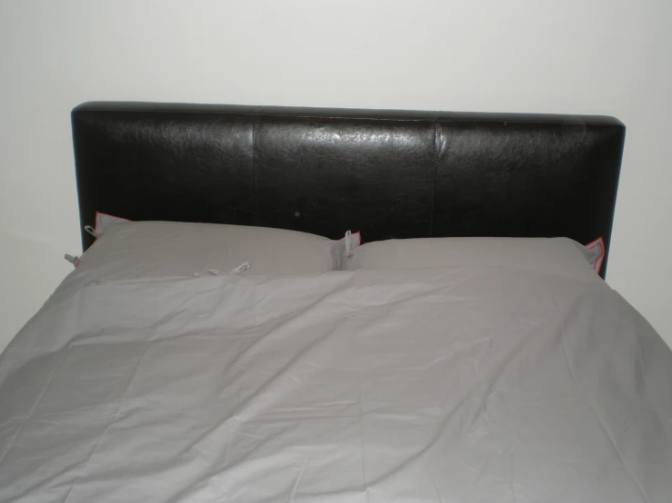 a single empty bed with white sheets and a black headboard