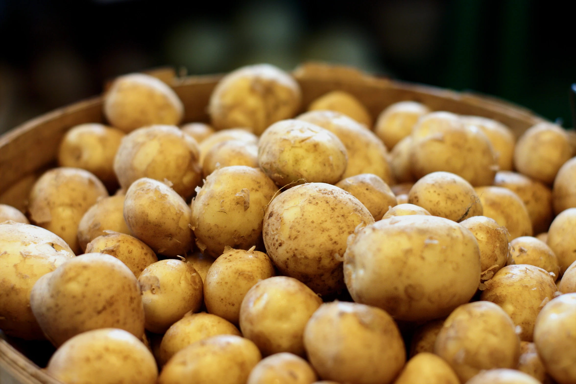 several bunches of potatoes are in a round basket