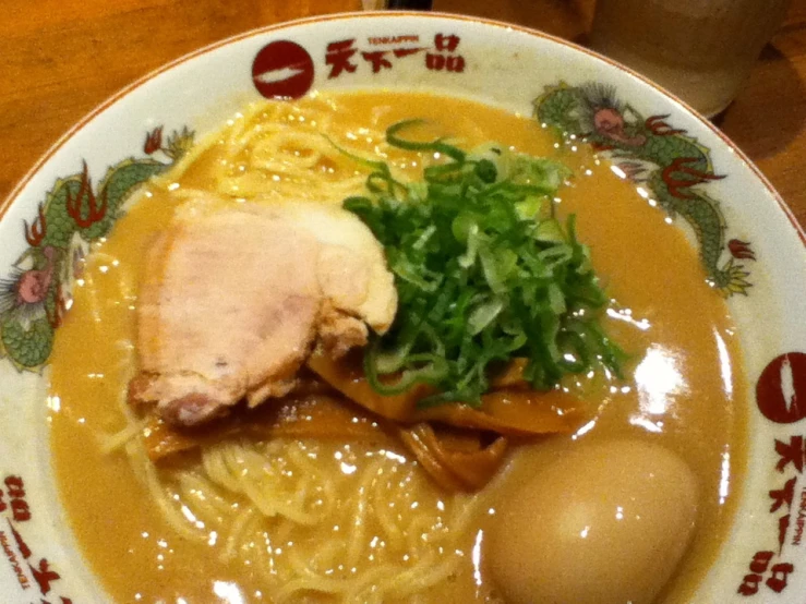 a plate with meat, noodles and a vegetable