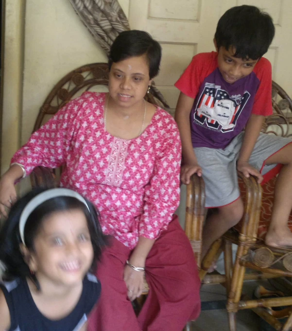 two people sitting on chairs with children around them