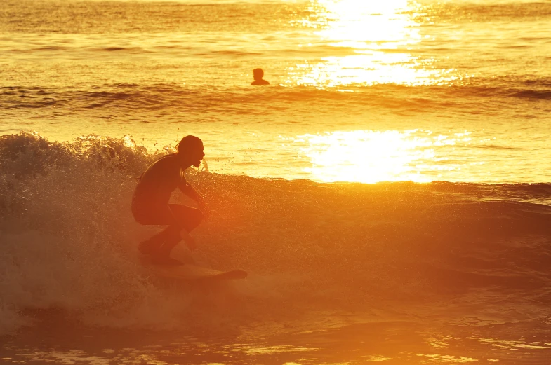 the sun is setting and a surfer is riding a wave