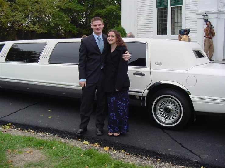 the man and woman are standing outside of the limo