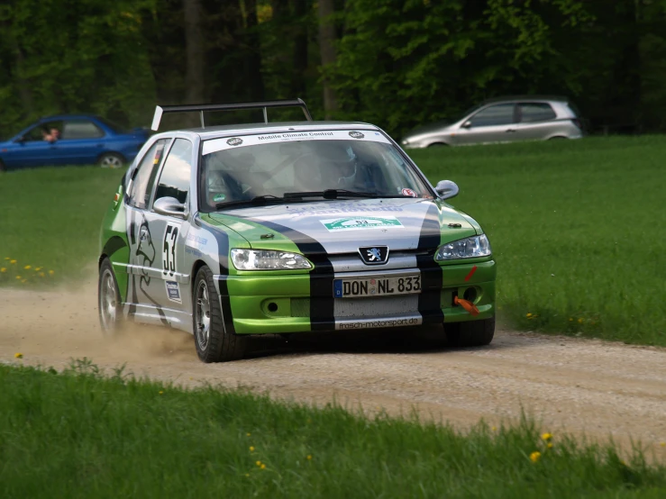 a green car driving on a dirt road