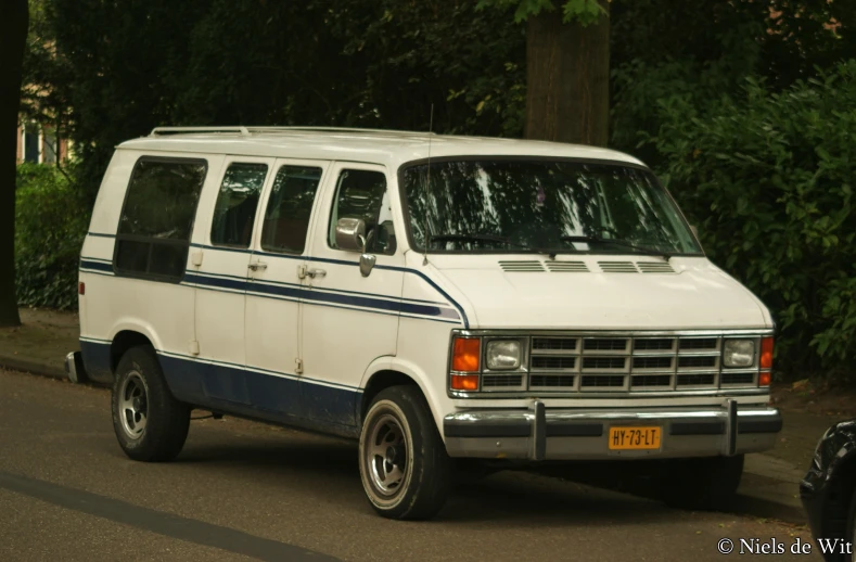 a white van that is parked next to some trees