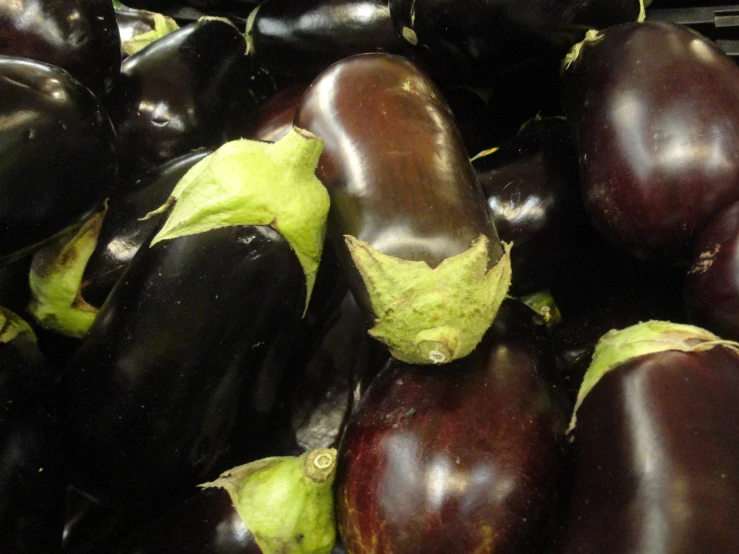 a bunch of eggplant in a bin sitting next to each other