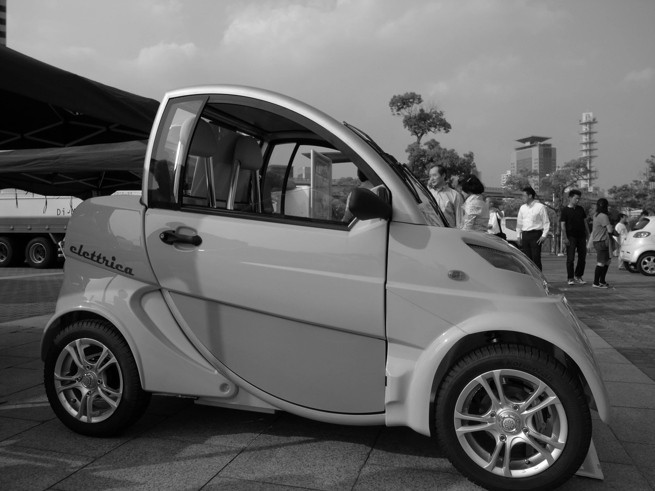 a small white car is parked at an outdoor event