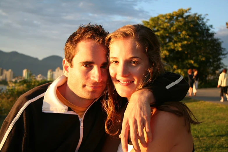 a beautiful young blond woman emcing a man in a park