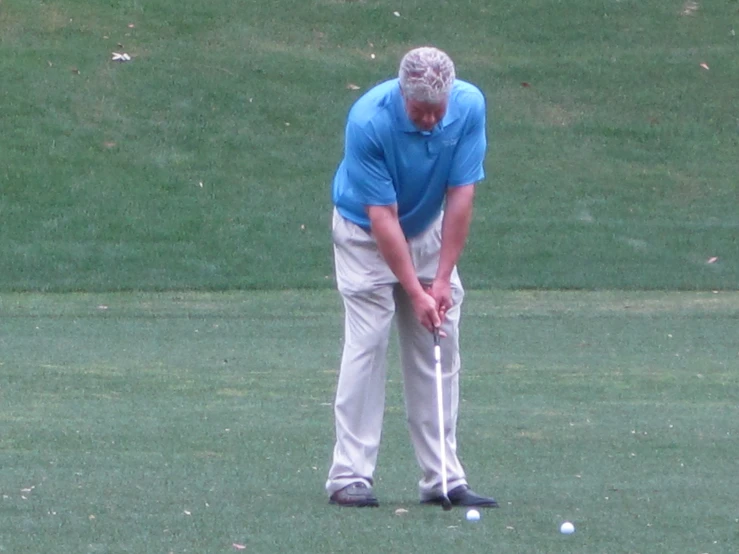 a man holding a golf club standing next to a white ball