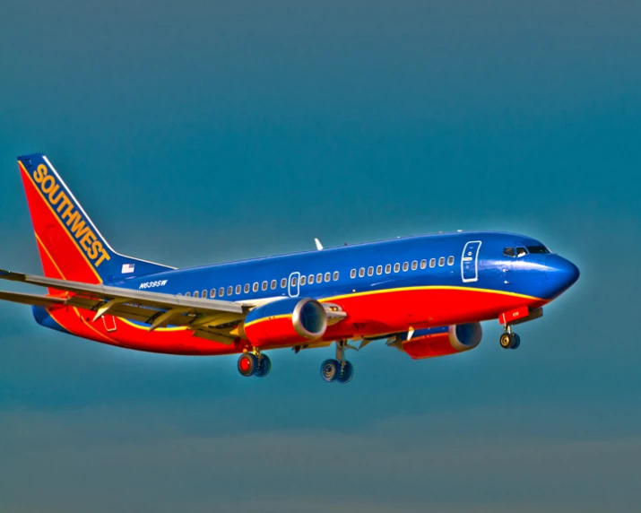 a jetliner flying through a blue sky with landing gear down