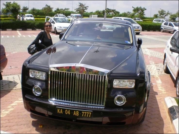 woman leaning on a rolls royce parked at the parking lot