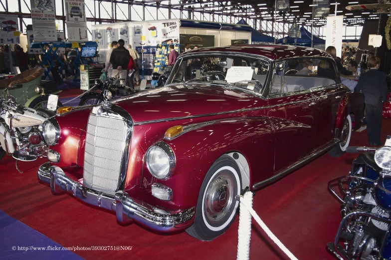 an old model red car on display at an auto show