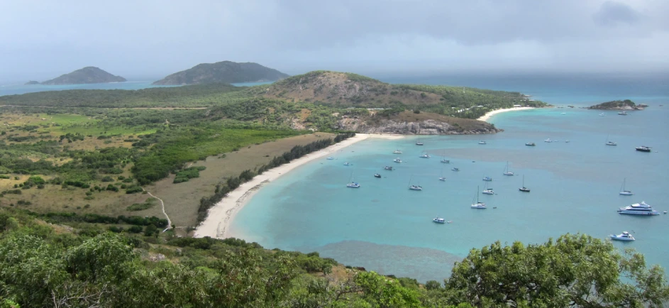 boats are on the ocean with a sandy beach