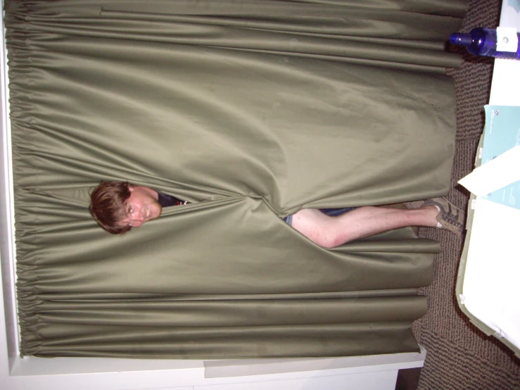 a man hiding his face behind a comforter