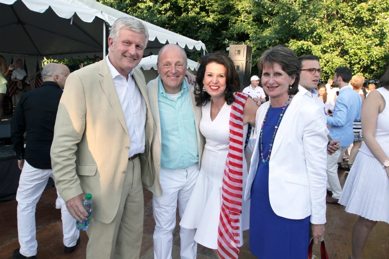 three people smile for the camera while standing next to a group of people