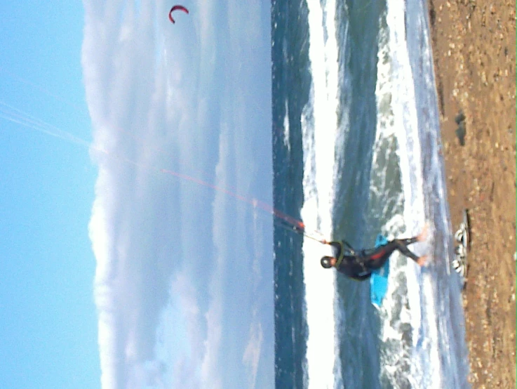 a man standing on top of a beach holding onto his kite