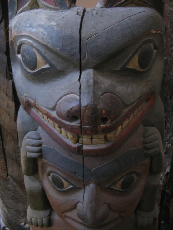 the carvings on the sides of a wooden pillar are depicting a man's face and his eyes